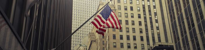 American flags waving among New York skyscrapers, showcasing urban patriotism.